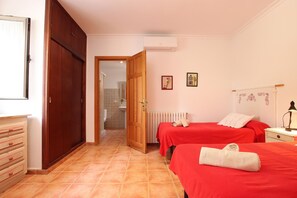 A bedroom with two beds, a wardrobe, a radiator, and a small bedside table. - Villa Provenza, Cozy villa with pool near Port Pollensa (Port de Pollença)