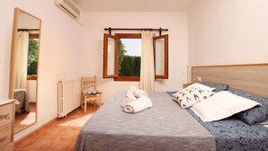 A bedroom with a bed, a chair, a dresser, a window with curtains, and a radiator. - Villa Provenza, Cozy villa with pool near Port Pollensa (Port de Pollença)