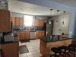 Kitchen features a central island, refrigerator, microwave, and stove, with ample natural light.
