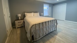 Une chambre à coucher avec un lit, des tables de chevet, un ventilateur de plafond et une fenêtre.