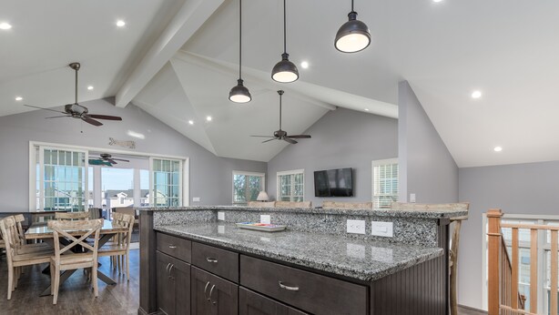Una cocina amplia con alacenas de madera oscura, encimeras de granito e iluminación colgante.