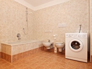 Een bad/douchecombinatie, een haardroger, een bidet, handdoeken