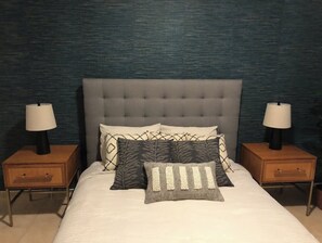 Cozy retreat with a tufted headboard, plush pillows, and bedside lamps.