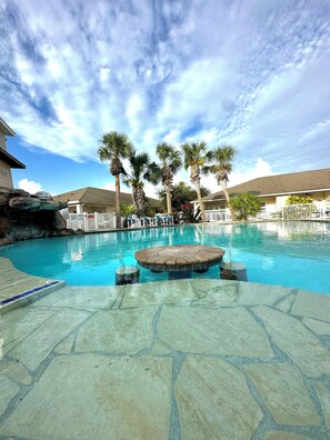 A swimming pool with a stone deck, palm trees, and a white fence. - Spacious Condo with Resort Style Pool Near Beach! (Corpus Christi)