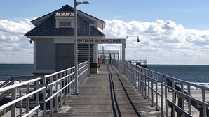 Un muelle que conduce a una estructura para pesca, con barandillas y vista despejada al océano.