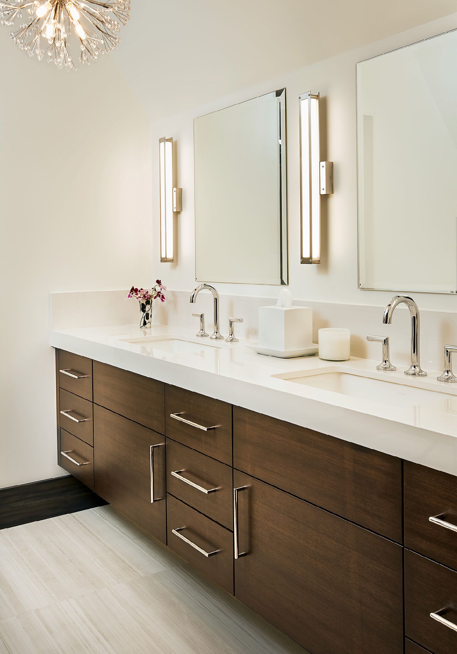 A modern bathroom with a double sink, two mirrors, and a wooden cabinet with drawers.
