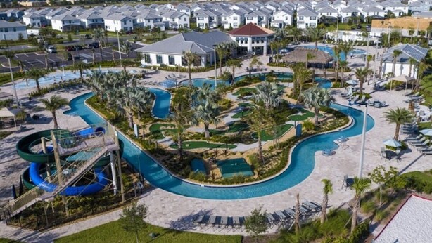 Eine Vogelperspektive zeigt ein Resort mit einem großen Schwimmbecken, Palmen und mehreren Gebäuden.