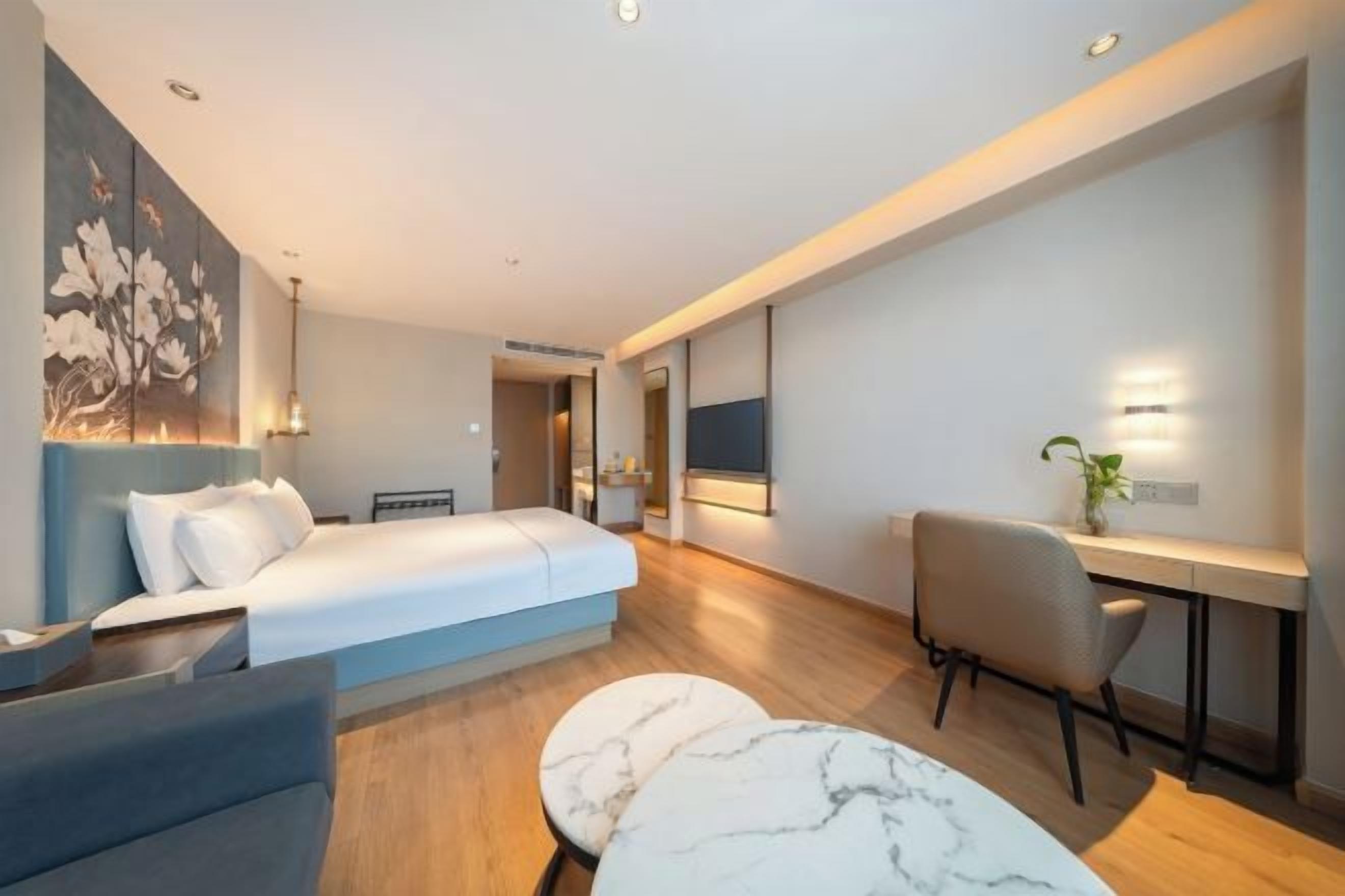 Ett modernt hotellrum med en säng, ett skrivbord, en stol och ett bord i marmor.