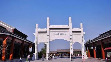 A traditional Chinese gate with inscriptions, surrounded by visitors and traditional architecture.