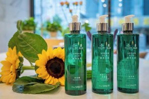 Three bottles of Urban Eco The SREM on a surface with a sunflower and green leaves in the background. - Magnotel Hotel (Xuzhou Suning Plaza) (Xuzhou)
