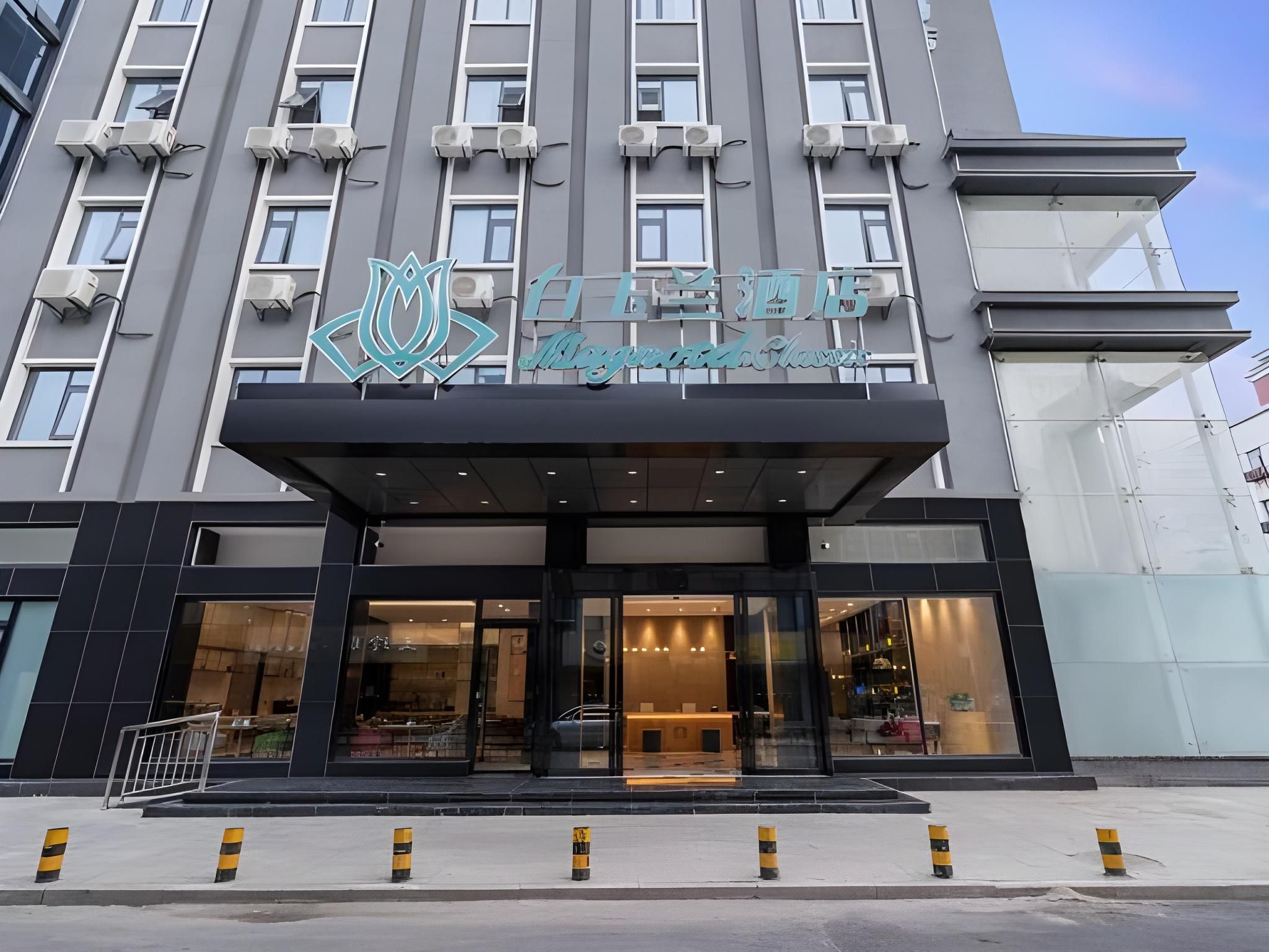 A hotel entrance with a modern design, featuring a prominent logo above the entrance and a glass facade.