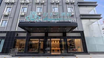 A hotel entrance with a modern design, featuring a prominent logo above the entrance and a glass facade.