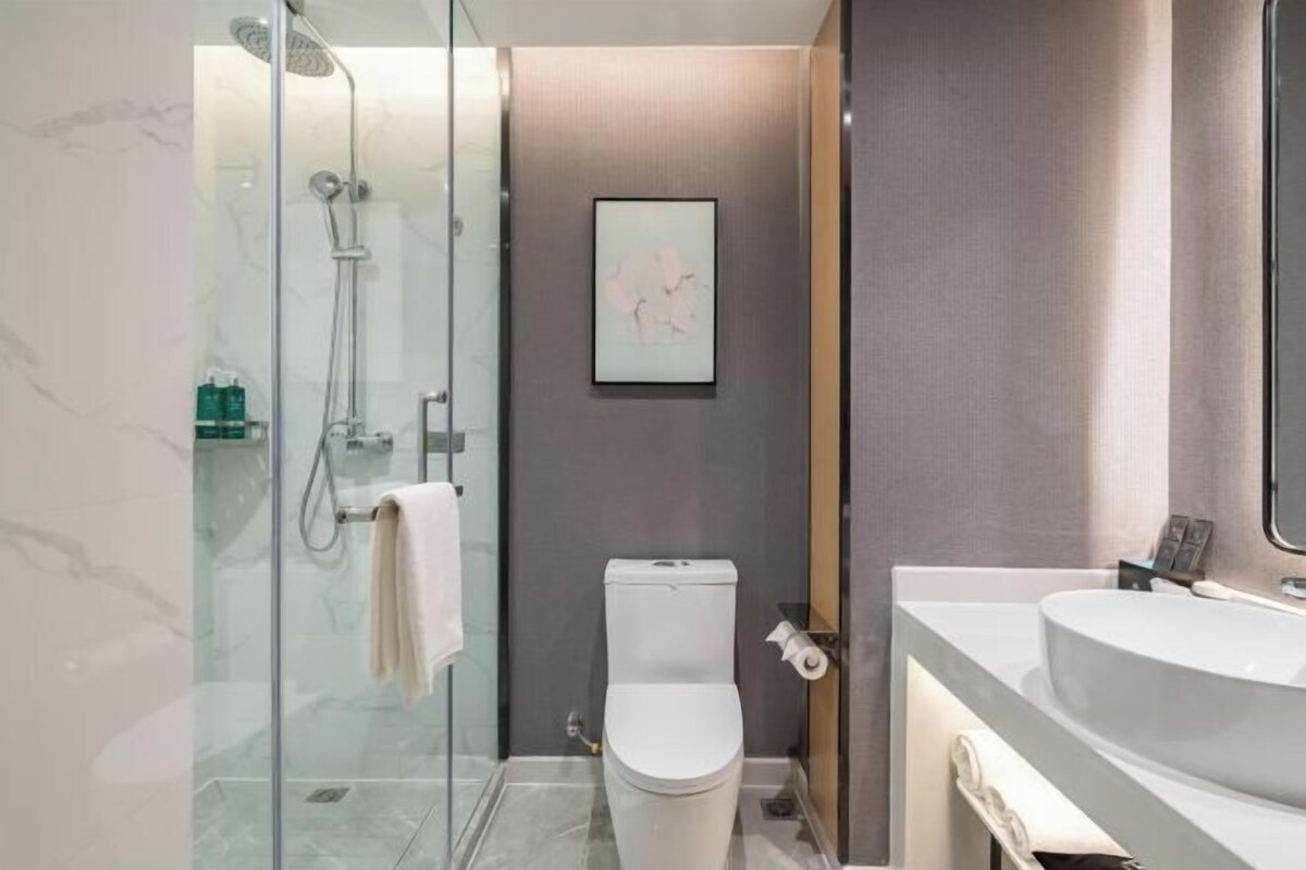 A modern bathroom with a glass shower enclosure, a toilet, and a large vanity with a mirror.