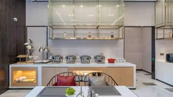 A modern kitchen with a central island, built-in appliances, and a glass-fronted upper cabinet.