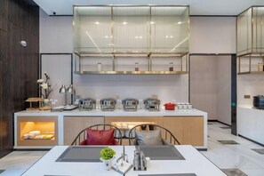 A modern kitchen with a central island, built-in appliances, and a glass-fronted upper cabinet. - Magnotel Hotel (Xuzhou Suning Plaza) (Xuzhou)