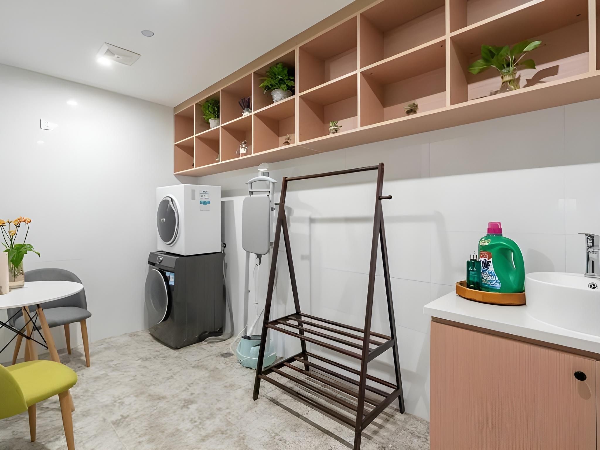 Une cuisine moderne équipée d’un lave-linge encastré, d’un étendoir et d’un plan de travail avec un évier et du liquide vaisselle.