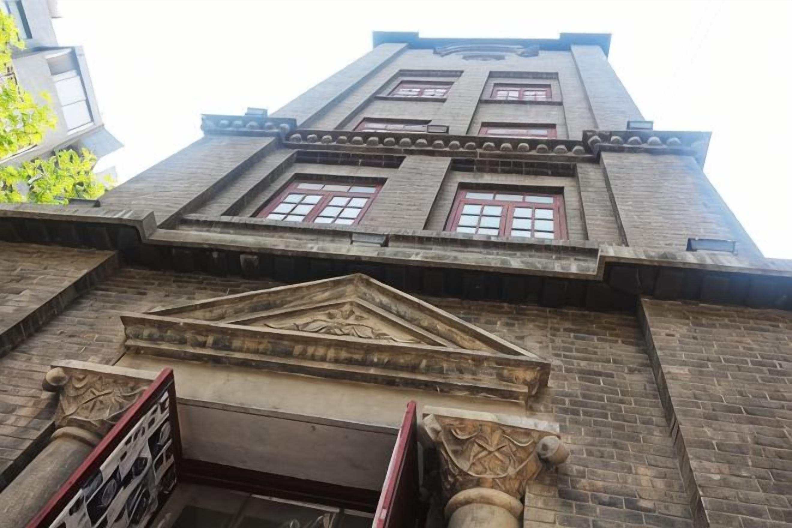 A building with a brick facade, multiple windows, and a central decorative element.