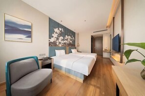 A hotel room with a bed, a desk, a chair, a TV, and a painting on the wall. - Magnotel Hotel (Xuzhou Suning Plaza) (Xuzhou)