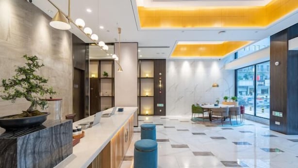 A modern hotel lobby with a reception desk, seating area, and large windows offering city views. - Magnotel Hotel (Xuzhou Suning Plaza) (Xuzhou)