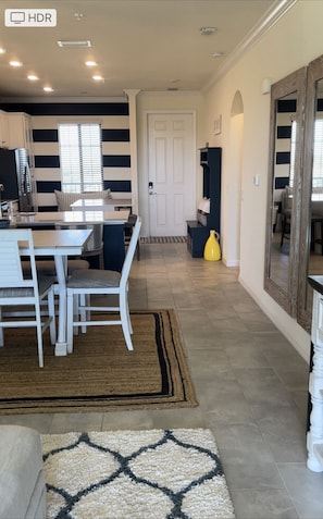 Una cocina moderna con comedor, una puerta blanca y un pasillo que conduce a una sala de estar.