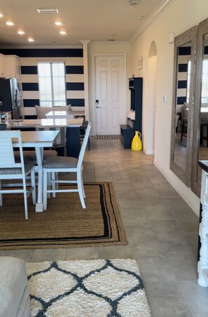 Una cocina moderna con comedor, una puerta blanca y un pasillo que conduce a una sala de estar.