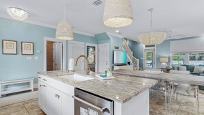 Een moderne keuken met een centraal eiland, roestvrijstalen apparatuur en hanglampen.