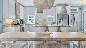 Een moderne keuken met witte kasten, een groot eiland en een kroonluchter.