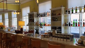 A bar area with shelves of liquor bottles, a bar counter with seating, and a window with a view of the street. - Prästgården Hotell & Bryggeri (Soderhamn)