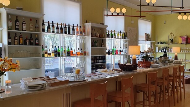 A bar area with shelves of liquor bottles, a variety of glasses, and a counter with bar stools. - Prästgården Hotell & Bryggeri (Soderhamn)