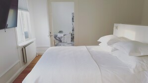 A neatly made bed with white linens in a room with wooden flooring and a white radiator. - Prästgården Hotell & Bryggeri (Soderhamn)