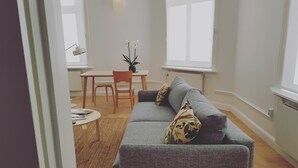 A living room with a grey sofa, a small round table, a wooden chair, and a potted plant. - Prästgården Hotell & Bryggeri (Soderhamn)
