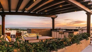 Eine Dachterrasse mit einer Pergola, einer Sitzgelegenheit und Blick auf die Stadtlandschaft.