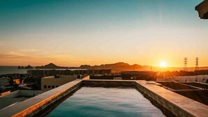 Ein Pool auf dem Dach mit Blick auf den Sonnenuntergang und entfernte Berge.