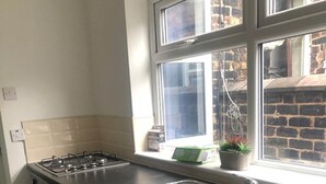 A compact kitchen with a gas stove, a washing machine, and a sink. - Townhouse @ Victoria Road Stoke (Stoke-on-Trent)