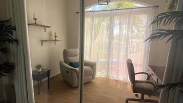 Ein Zimmer mit einer Schiebeglastür, die zu einem Außenbereich mit einem Stuhl und einem Tisch führt.