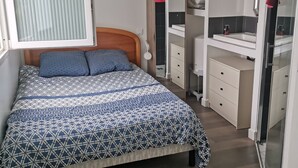 A bedroom with a bed, a bedside table, a wardrobe, a mirror, and a hanging light fixture.