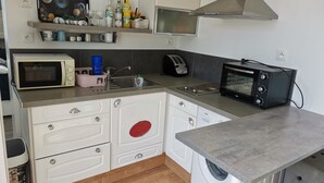 A compact kitchen with a microwave, toaster, sink, and a washing machine.