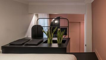 Une chambre d’hôtel moderne comprenant un lit, un bureau avec une chaise, une plante en pot et une armoire.