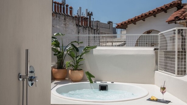 Un baño al aire libre moderno con un jacuzzi, plantas en macetas y un cabezal de ducha.