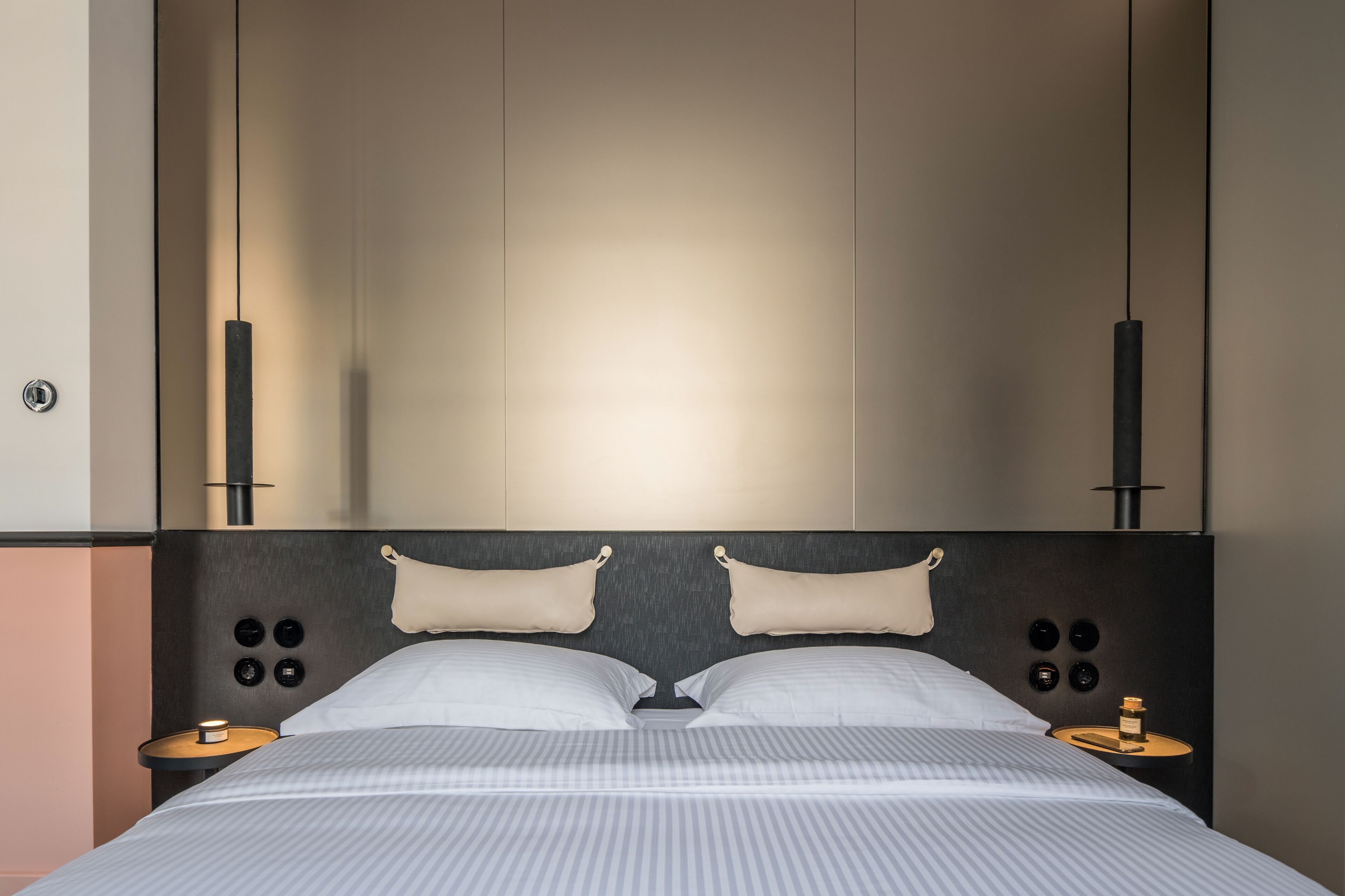 Une chambre moderne avec un grand lit, deux tables de chevet et une tête de lit dotée d’un éclairage intégré.