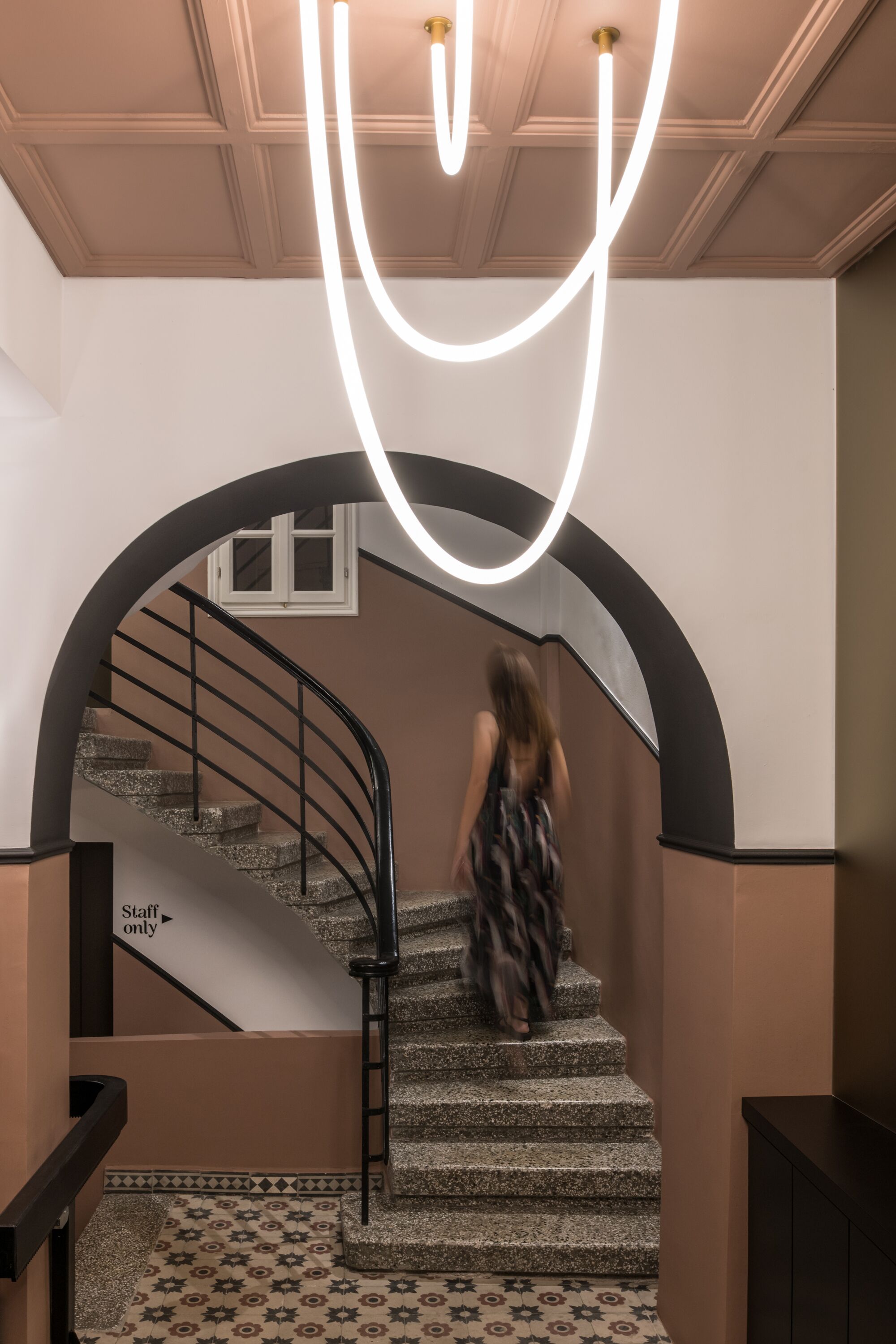 Una escalera con barandilla negra, un cartel que dice 'Solo personal' y un suelo estampado.