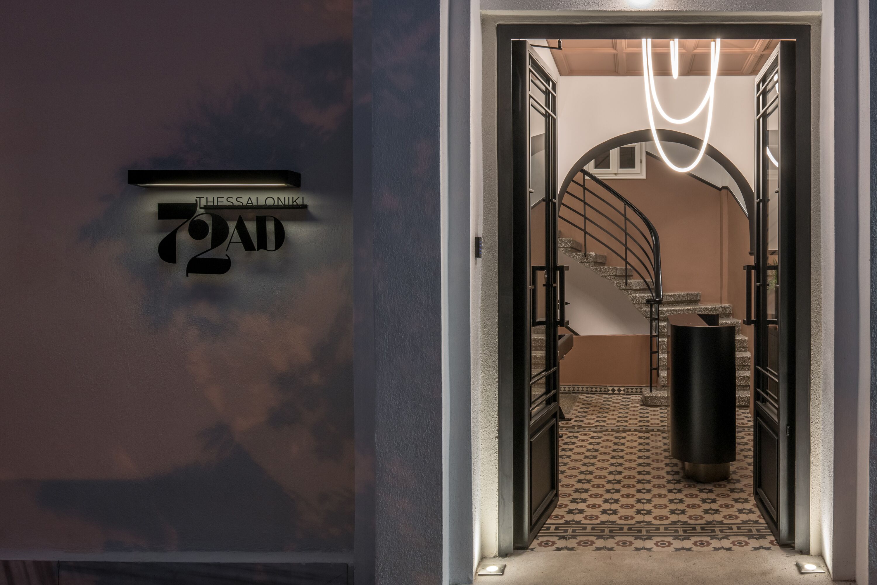 A modern hotel entrance with a staircase leading to a second floor.