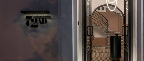 A modern hotel entrance with a staircase leading to a second floor.