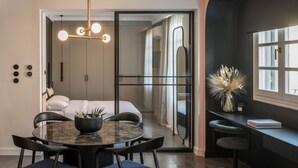 Una habitación moderna con una mesa redonda de comedor, sillas, una planta en maceta y un espejo grande.
