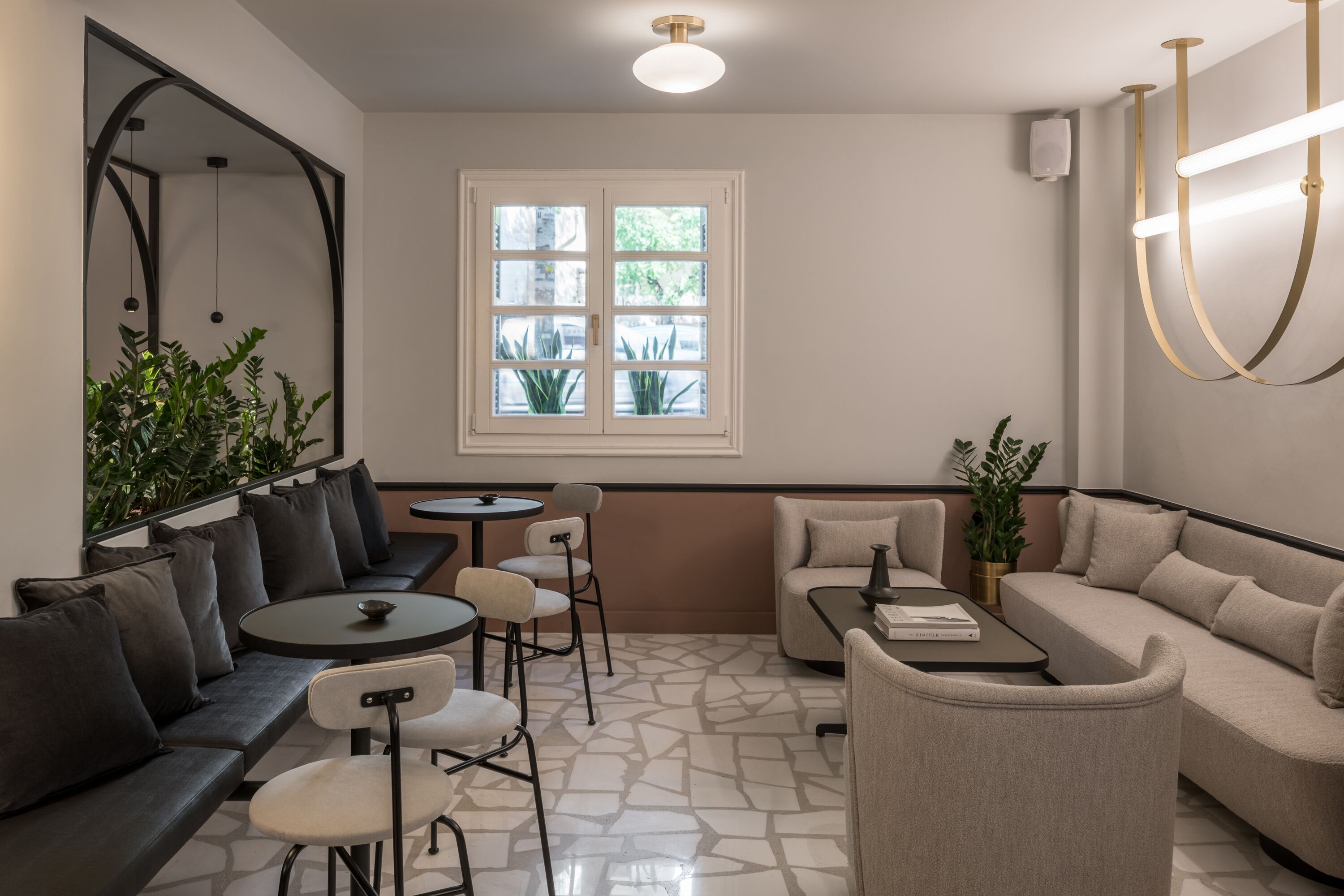 A modern interior with a seating area, a window with plants, and a light fixture.