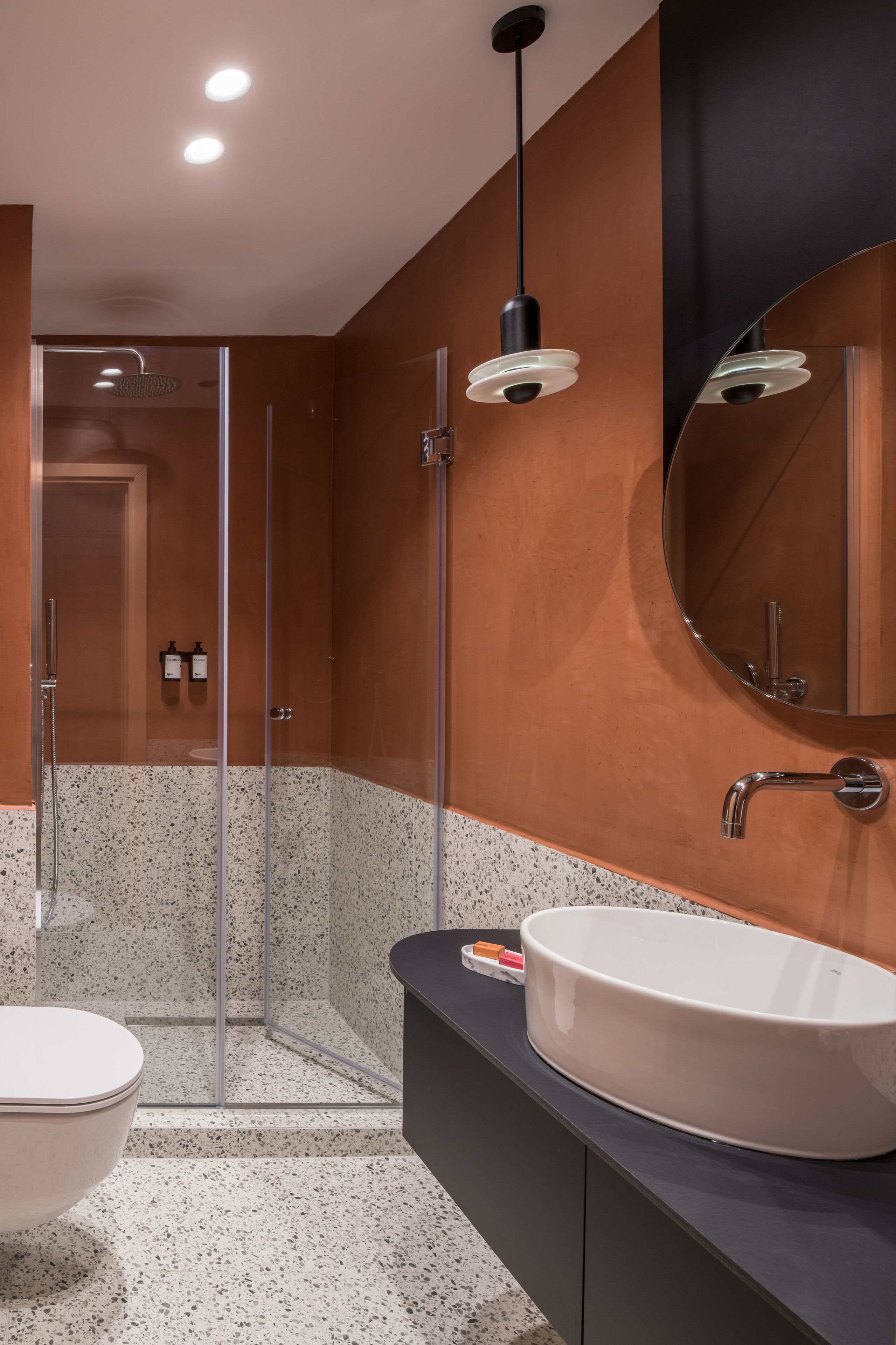 A modern bathroom with a glass-enclosed shower, a large sink, and a mirror.