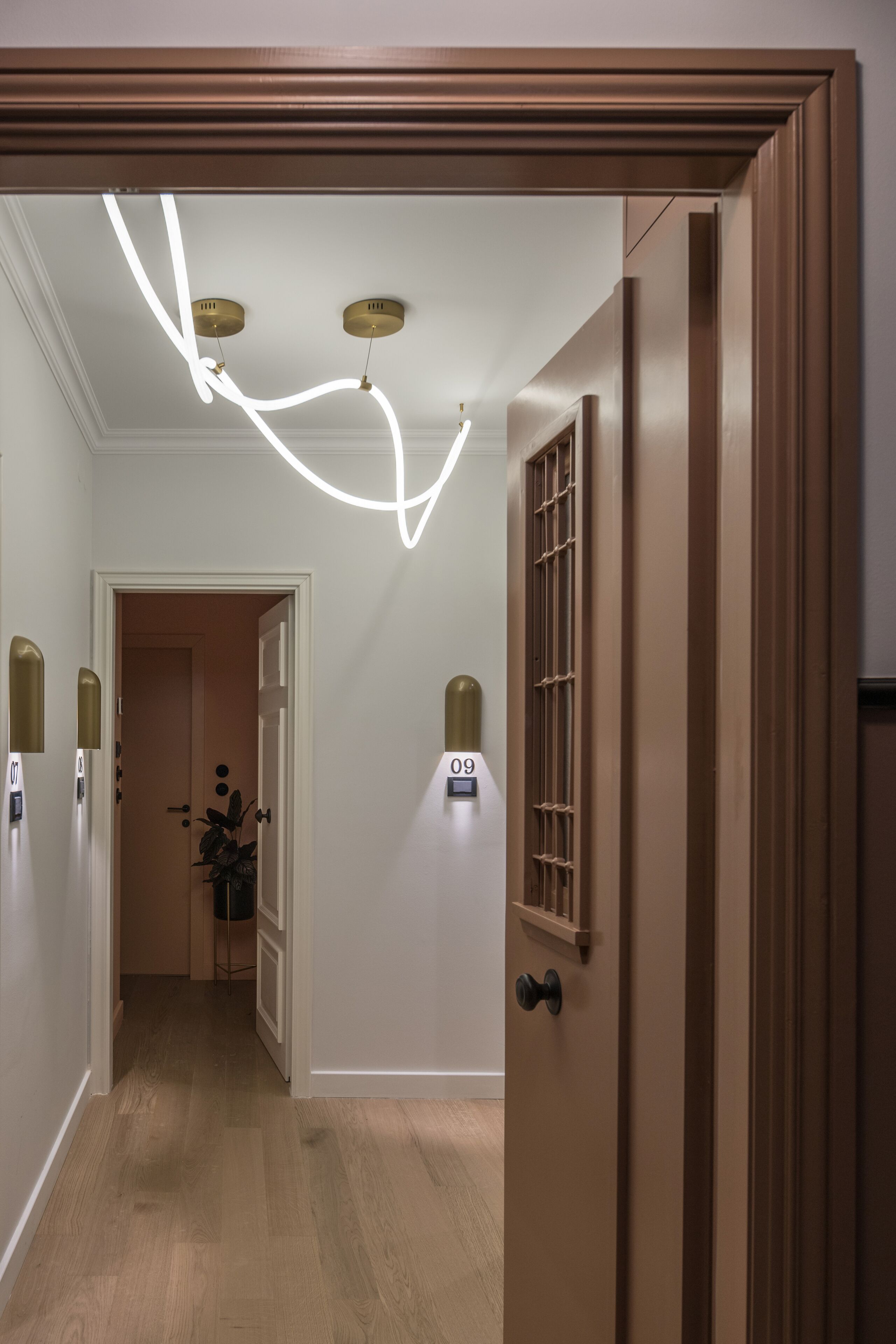 A hallway with a wooden door, a light fixture, and a wall-mounted light.
