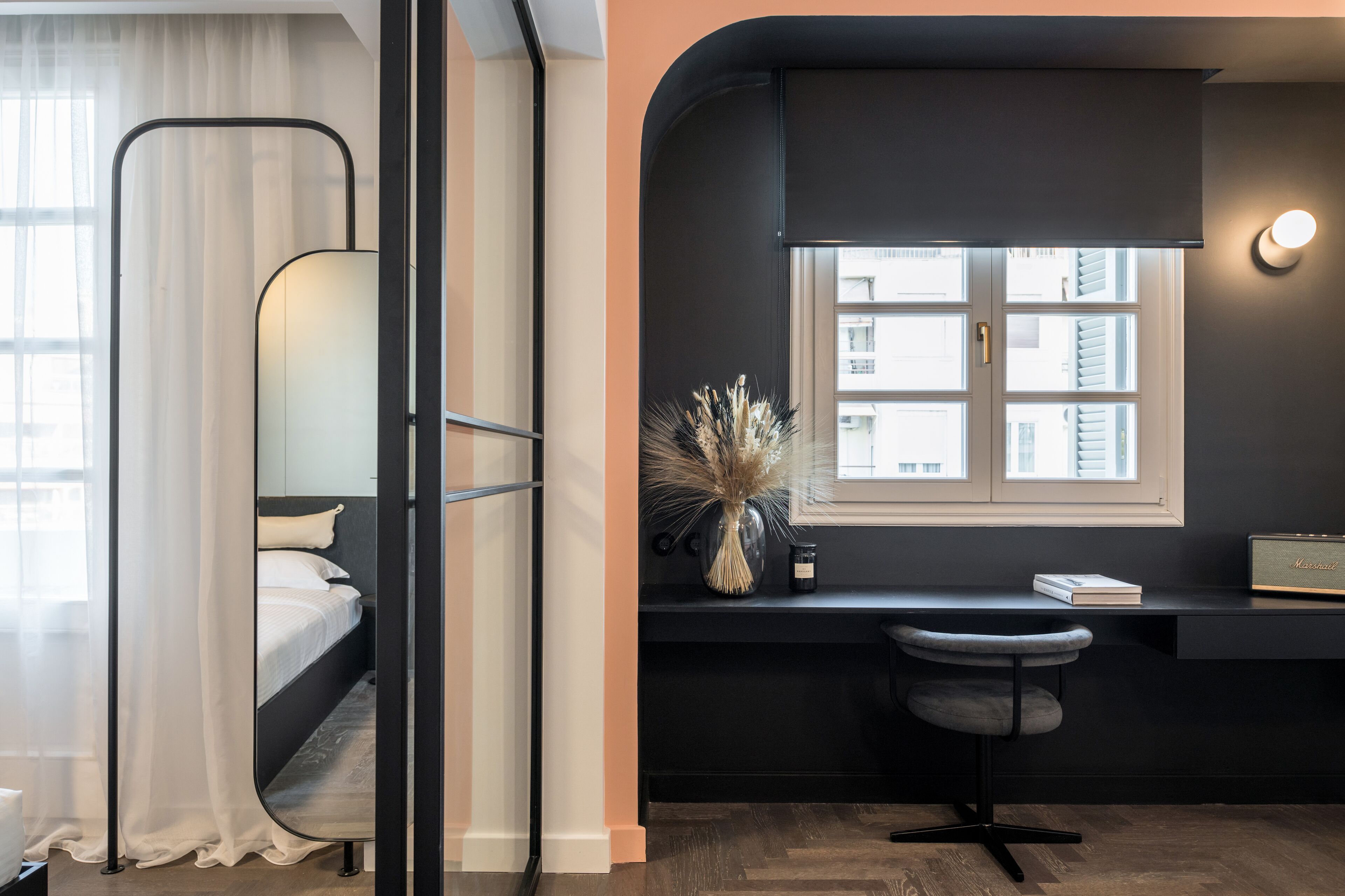 Ein modernes Schlafzimmer mit Bett, Nachttisch, Schreibtisch mit Stuhl, Fenster und Spiegel.
