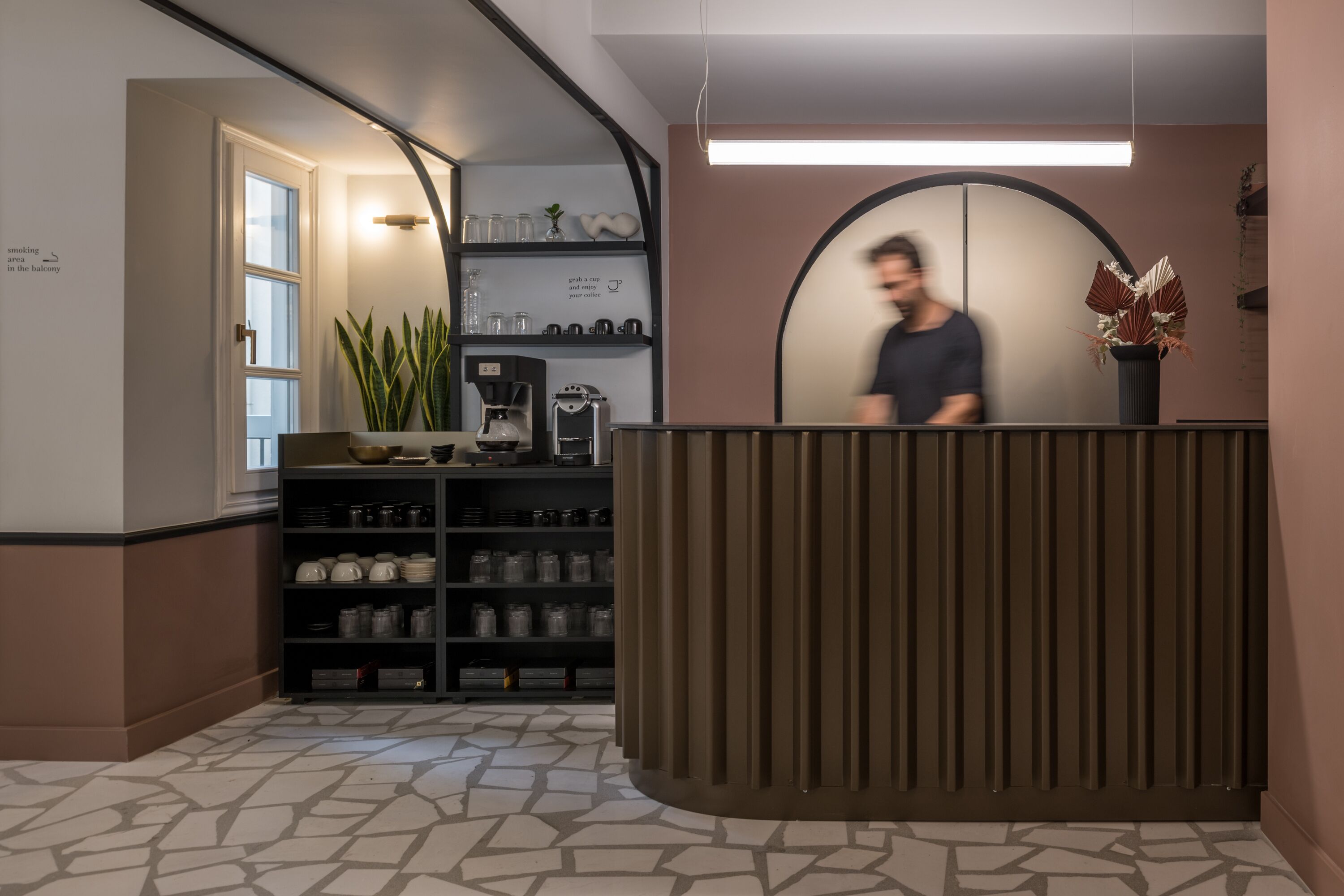 A reception area with a counter, shelves with kitchenware, and a potted plant.