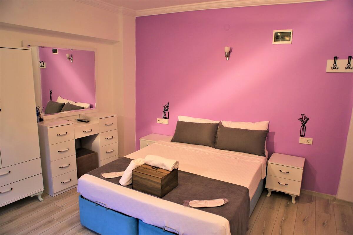 A bedroom with a bed, a dresser, a nightstand, and a mirror.